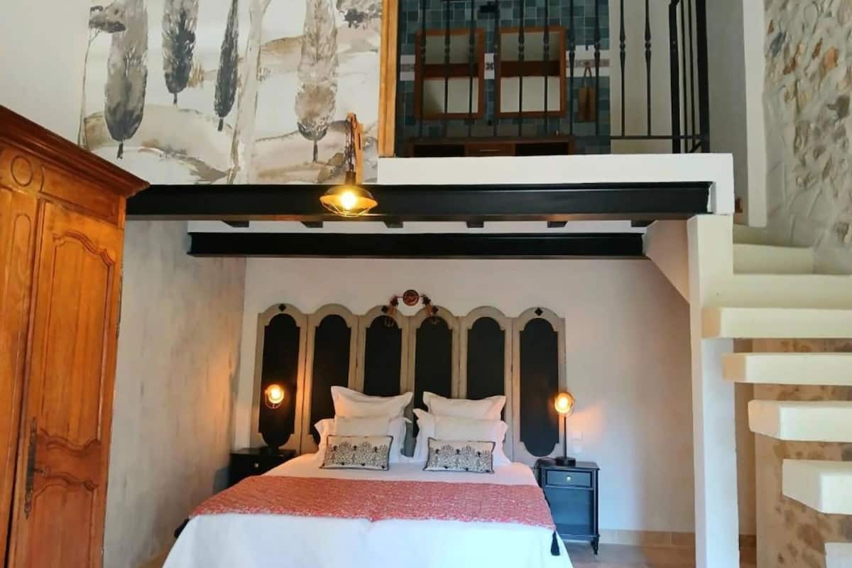 Un dormitorio con una cama grande, un armario de madera, un balcón con barandilla y un techo decorativo.