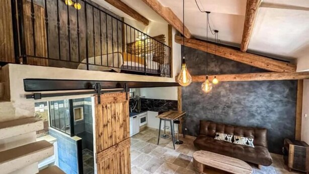 Amplia sala de estar con escalera, cocina y área de descanso con sofá y mesa de centro.