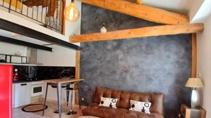 Una sala de estar moderna con un sofá, una mesa de centro y una zona de comedor con una cocina al fondo.