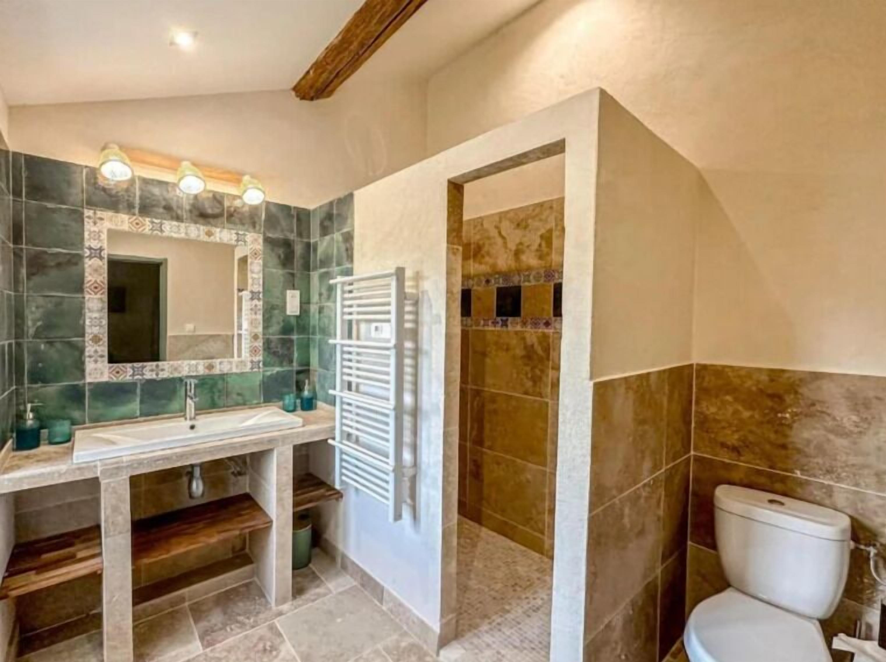 Une salle de bain équipée d’un lavabo, d’un miroir et d’un espace douche.