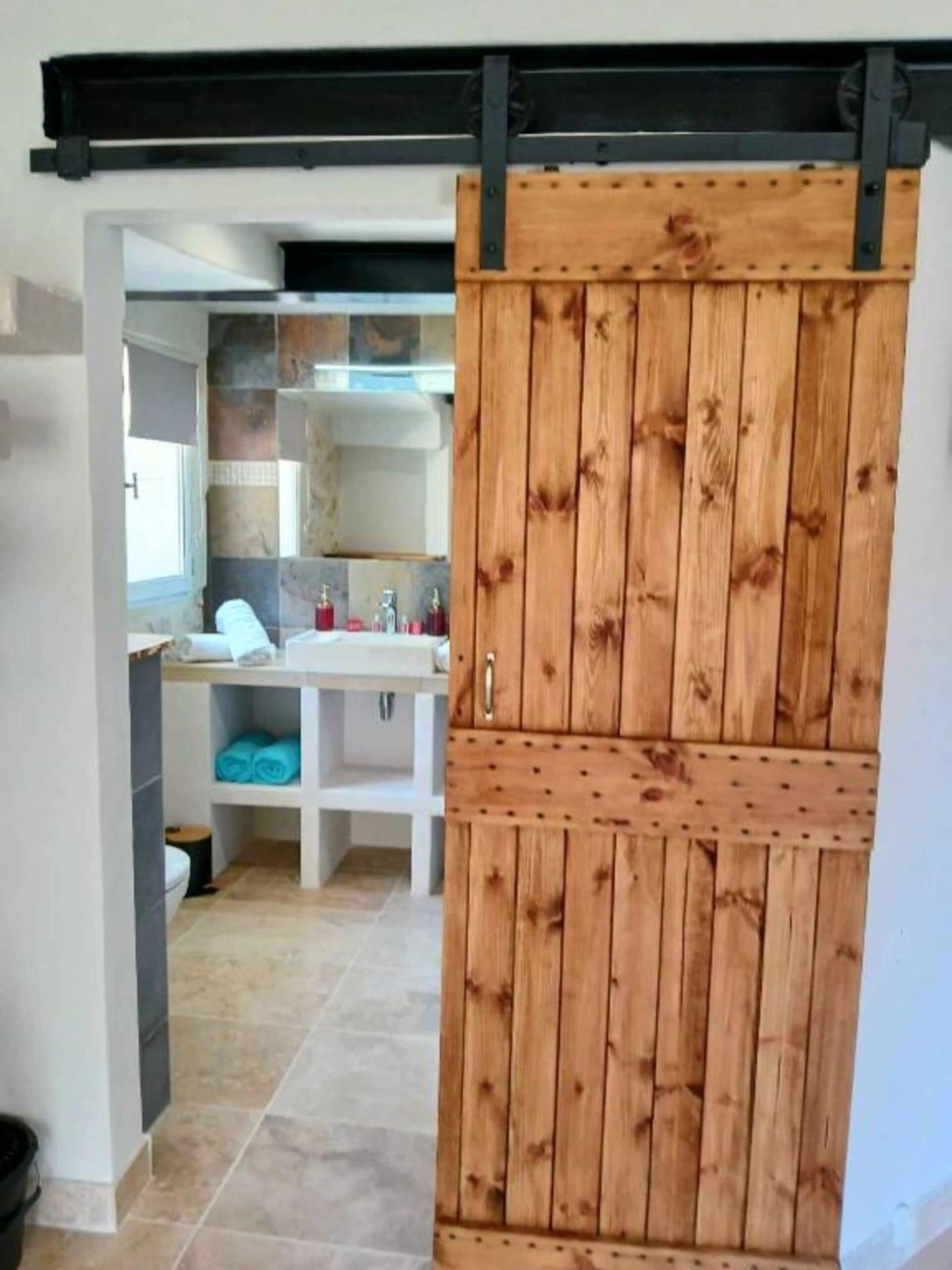 A bathroom with a wooden sliding door, a white sink, and a towel rack.
