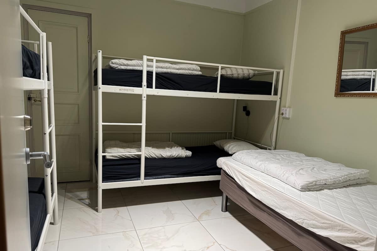 A bunk bed room with a door, a mirror, and a tiled floor.