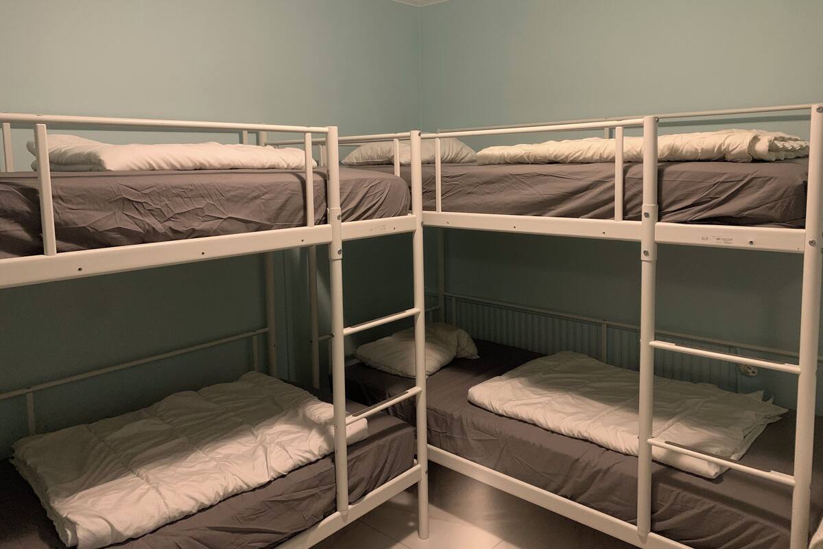 A bunk bed room with four beds, each with a mattress and pillows.