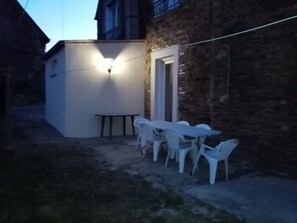 A patio area with a white table and chairs, a small round table, and a light fixture on the wall. - MAGNIFICENT BRETON HOUSE - VIEW OF MONT ST MICHEL - ideal for family reunion. (Sougeal)