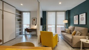 A modern living room with a sofa, a yellow armchair, a dining table, and a desk with a chair. - CALM APARTMENTS presents its PREMIUM APARTMENT in the heart of Barcelona. (Barcelona)