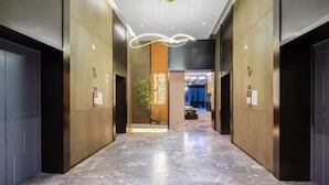 Eine moderne Hotelhalle mit Marmorböden, Holzvertäfelung und einem zentralen dekorativen Element.