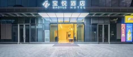 The exterior of Baoyue Hotel with a glass facade and a well-lit entrance.