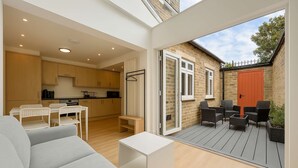 Eine moderne Wohnung mit Essbereich, Küche und einer Terrasse mit Gartenmöbeln.