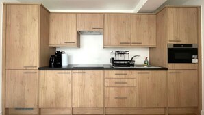 Eine moderne Küche mit Holzschränken, einer schwarzen Arbeitsplatte, einem eingebauten Ofen und einem Spülbecken.