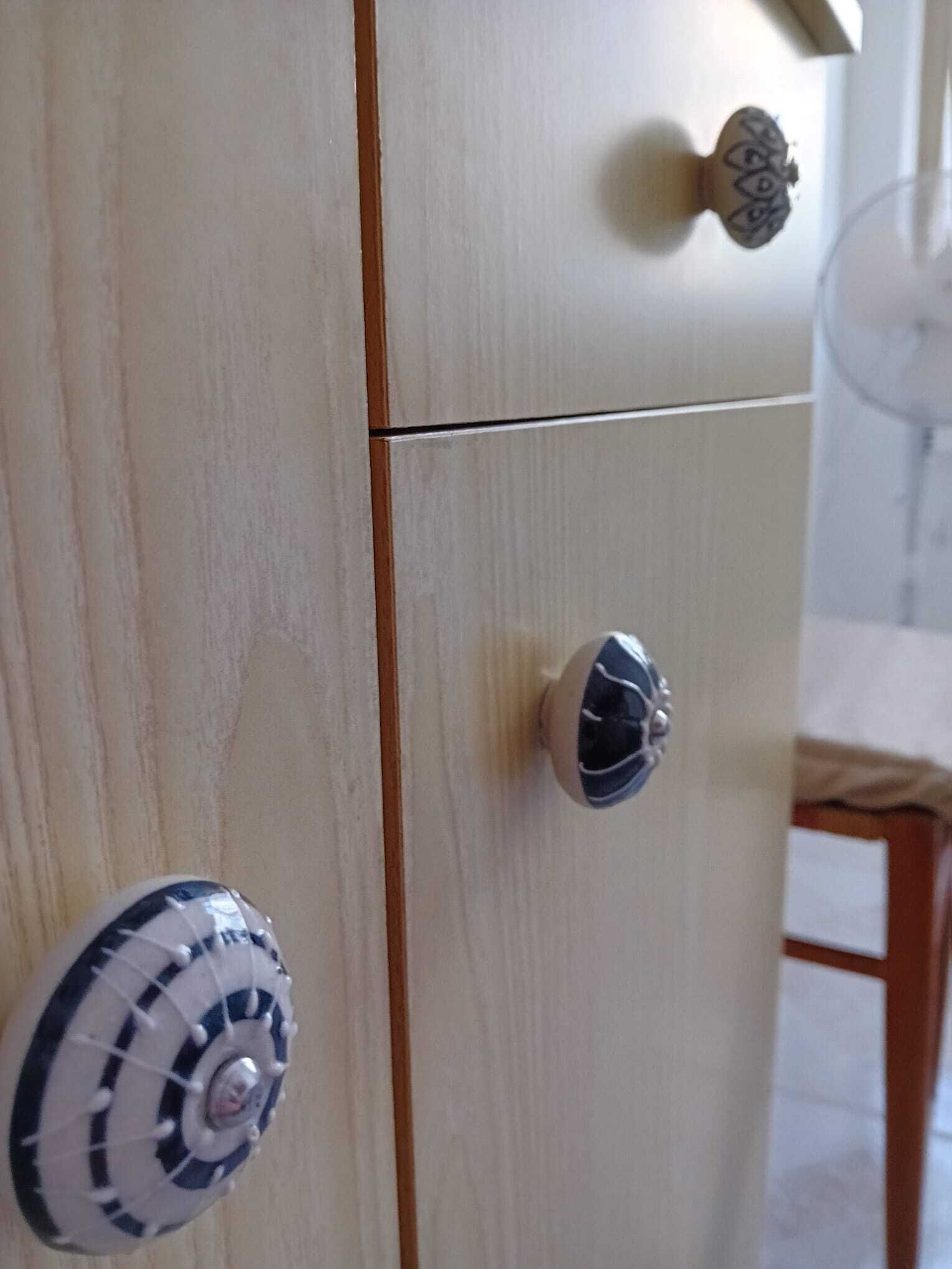 Un mobiletto in legno con due cassetti, ognuno dotato di una maniglia decorativa.