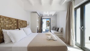 A modern hotel room with a large bed, a wooden headboard, and a view of the outside. - Noble Pearl Villa 3 

Charming 4-bedroom Villa with Swimming pool & Jacuzzi (Paros)