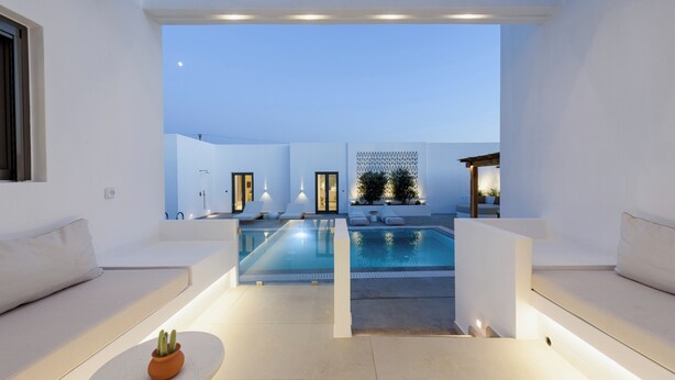 A modern outdoor pool area with white walls and seating, a clear view of the sky, and a small potted plant on a table. - Noble Pearl Villa 3 

Charming 4-bedroom Villa with Swimming pool & Jacuzzi (Paros)