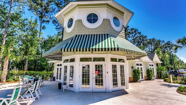 A white octagonal building with a green roof and striped awning, surrounded by trees and outdoor seating. - Beautiful World Tour 3B3Ba Condo on 12th Hole. Pool Access. Close to Everything! (Myrtle Beach)