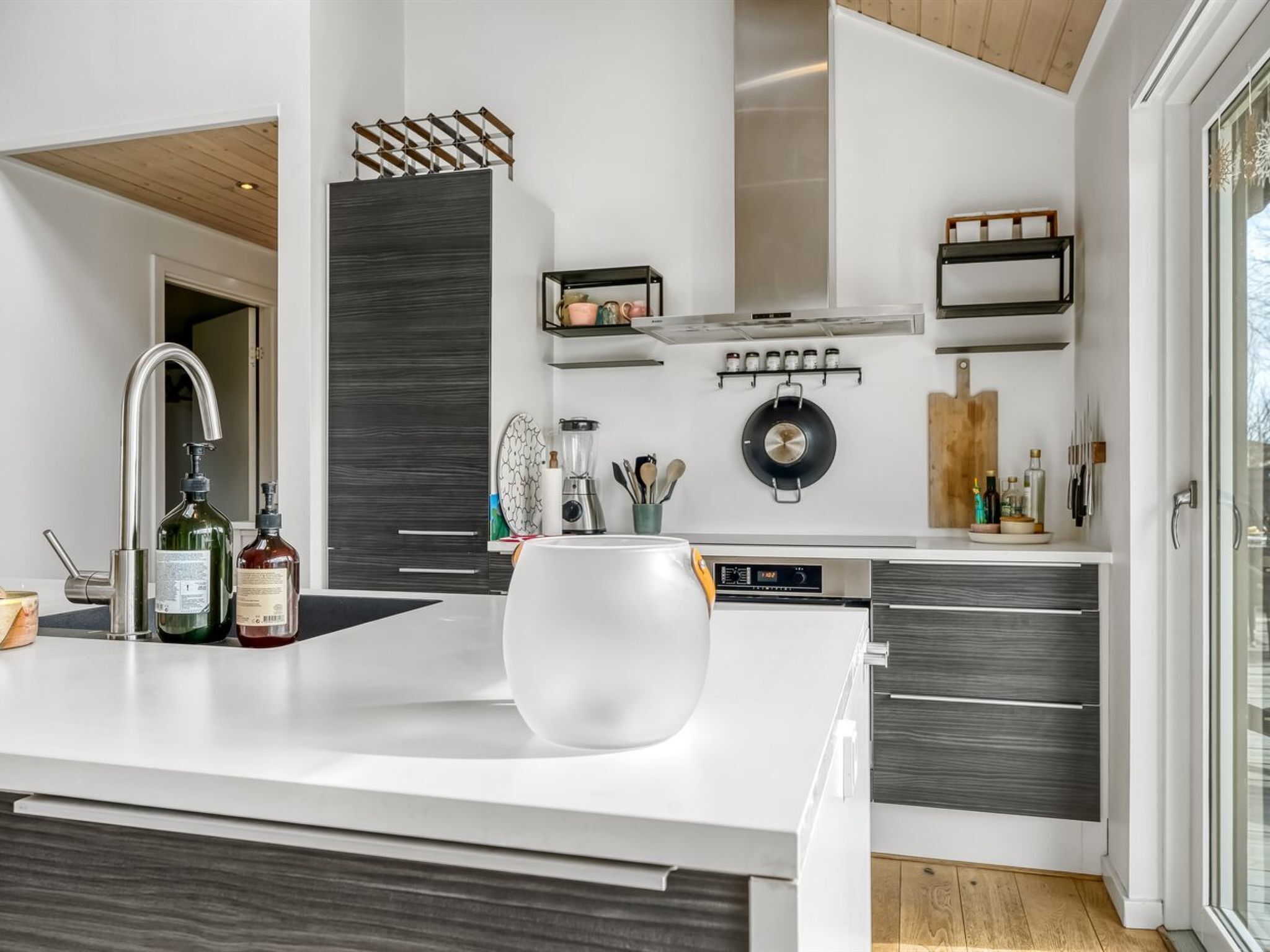 A modern kitchen with a central island, built-in appliances, and a large window providing natural light.
