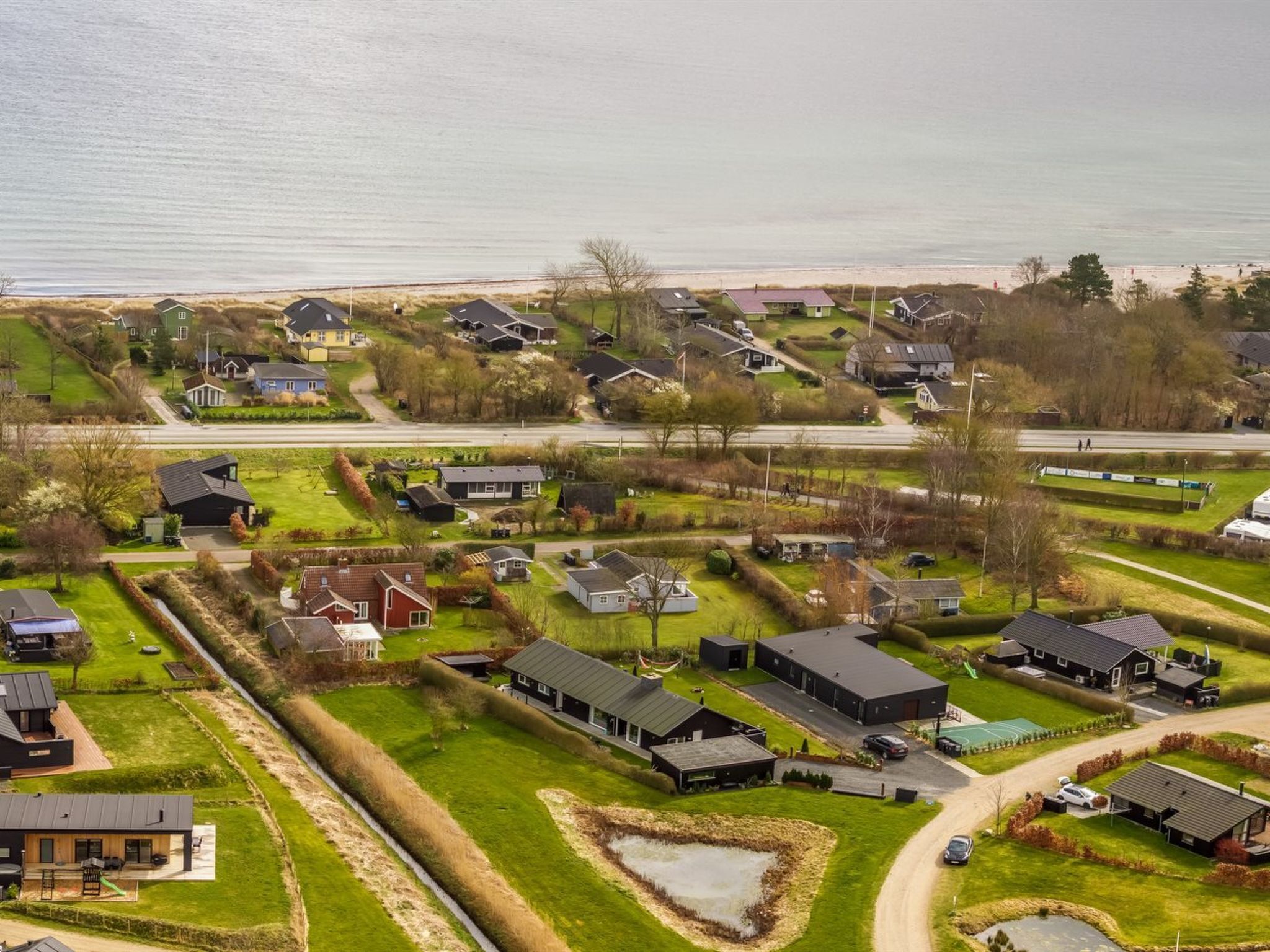 Ett bostadsområde med hus, en väg och en strand i bakgrunden.