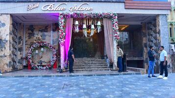 The entrance of Hotel Blue Stone with a floral archway and a staircase leading inside.