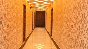 A hallway with patterned wallpaper and a geometric ceiling design. - Hotel Blue Stone (Kanpur)