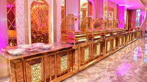A long, reflective, gold-toned reception desk with intricate lattice designs and a mirrored backdrop. - Hotel Blue Stone (Kanpur)