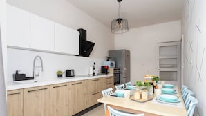 A modern kitchen with white cabinets, a wooden countertop, and a dining area with a table set for four.