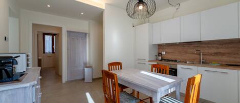 A modern kitchen with white cabinets, a wooden countertop, and a dining area with a white table and wooden chairs.