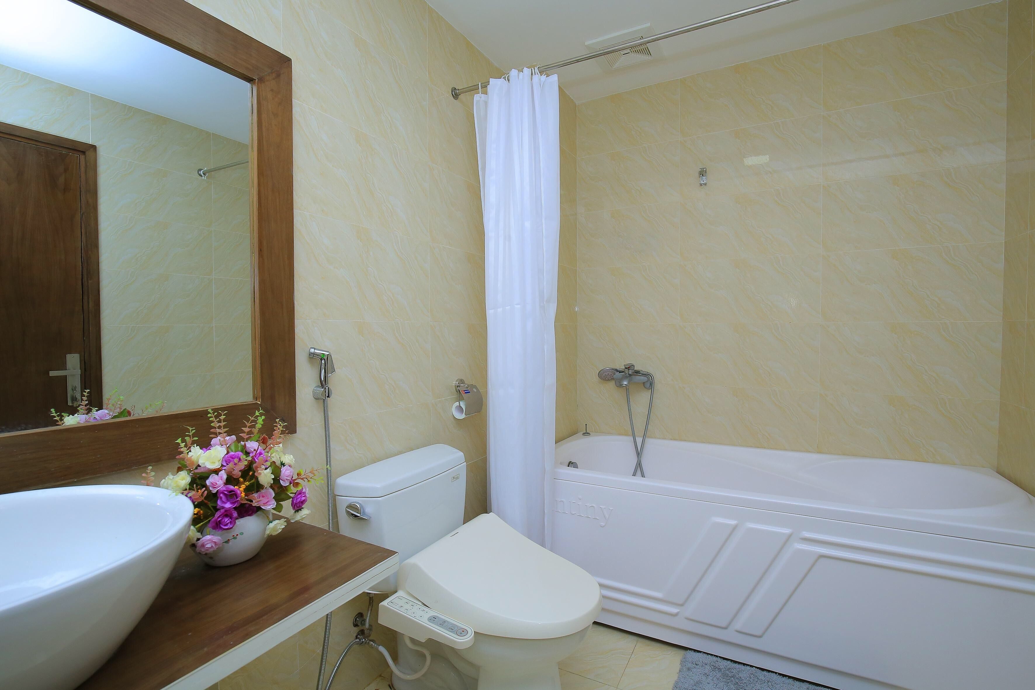 Ein Badezimmer mit Badewanne, Toilette, Waschbecken und Spiegel.