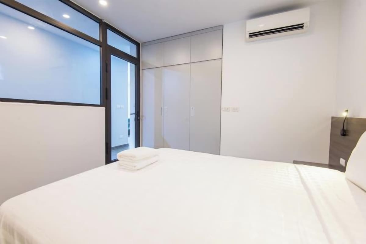Quarto de hotel moderno com uma cama grande, um guarda-roupa e um ar condicionado na parede.