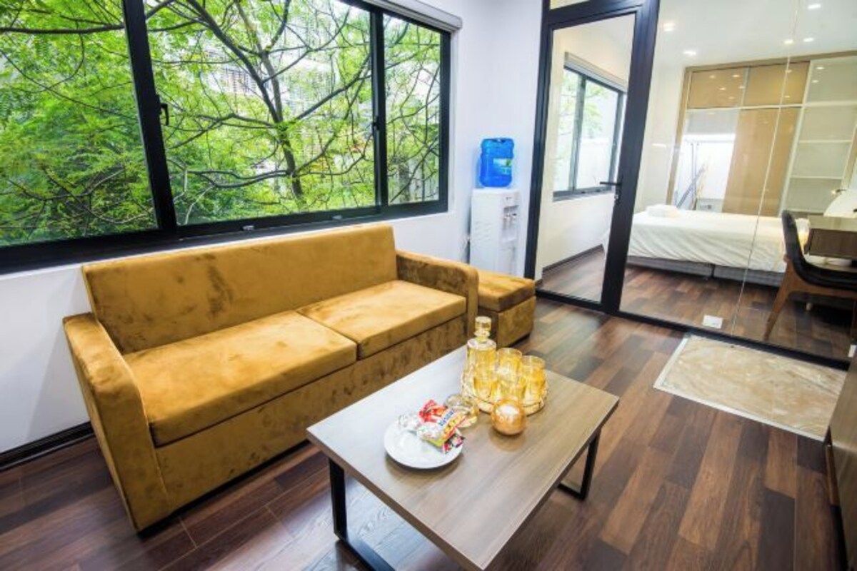 Ein modernes Wohnzimmer mit einer Couch, einem Couchtisch mit Dekoration und einem großen Fenster mit Blick auf Bäume.