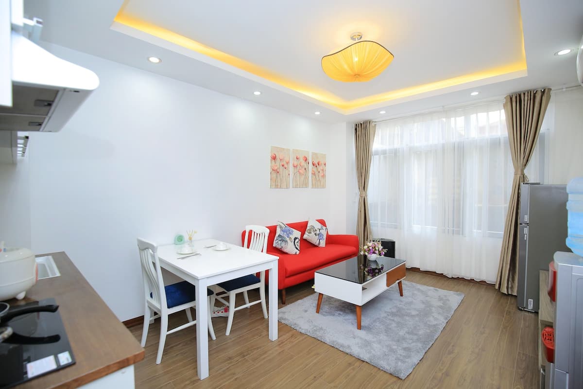 A modern living room with a red sofa, white coffee table, and a dining table with chairs.
