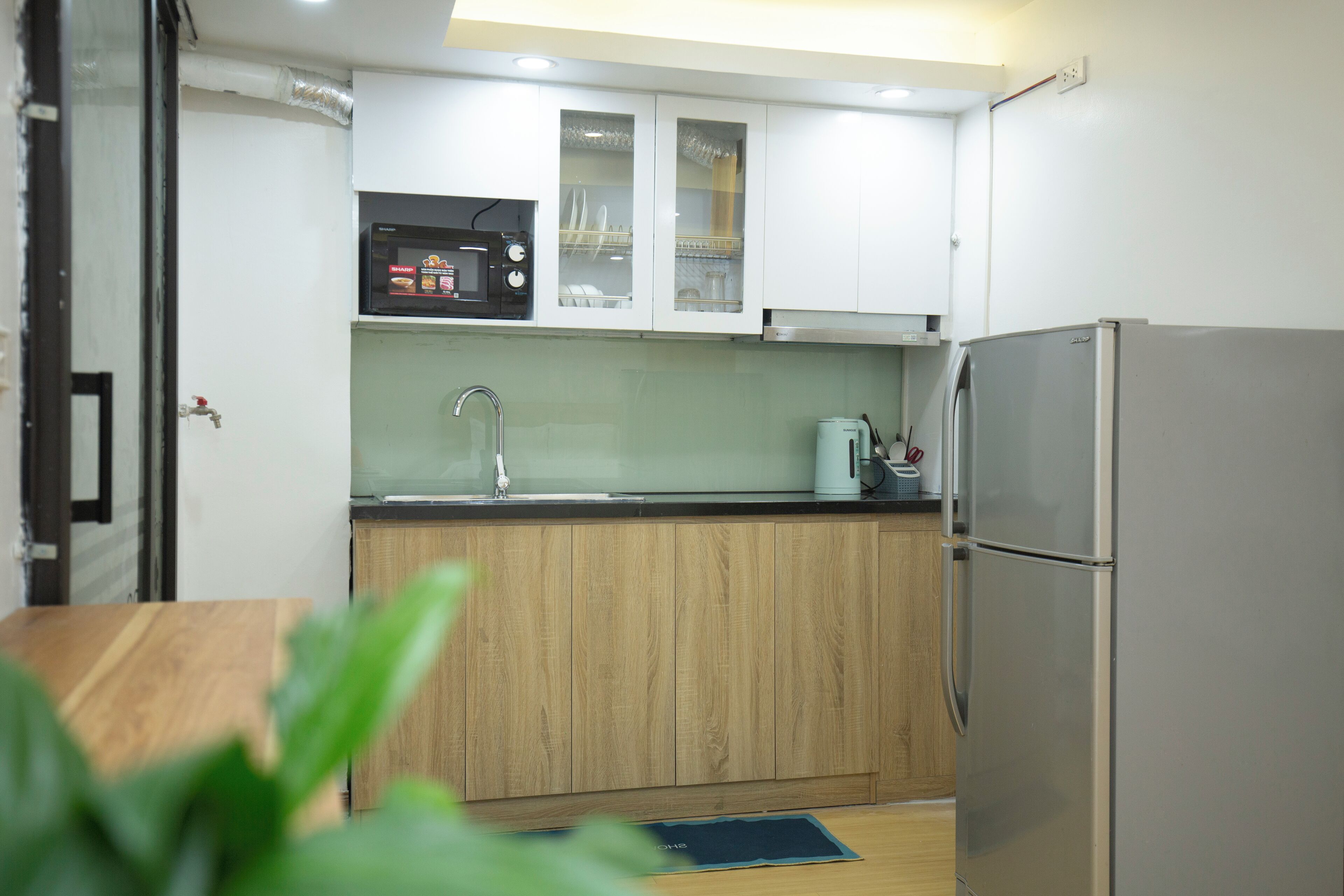 Una cocina moderna con armarios de madera, un refrigerador de acero inoxidable y un microondas.