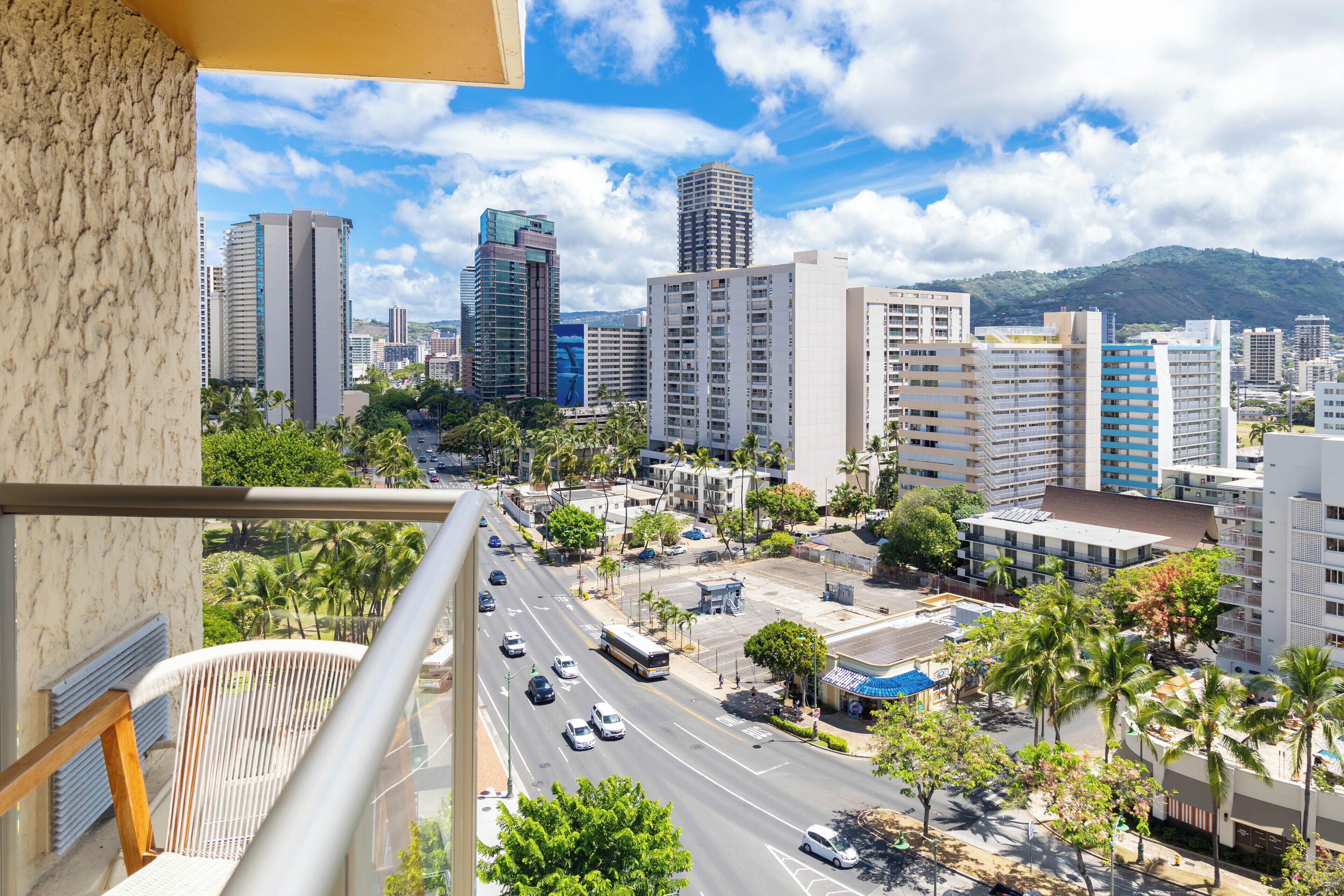 A cityscape with tall buildings, a busy street, and palm trees.