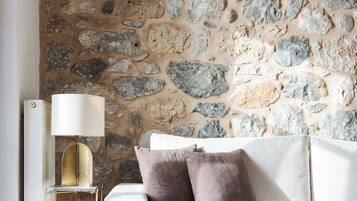 A modern living room with a stone wall, a white sofa, and a lamp.