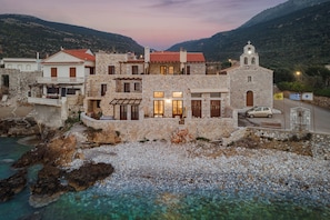 A coastal stone building with multiple rooms, a balcony, and a small church.