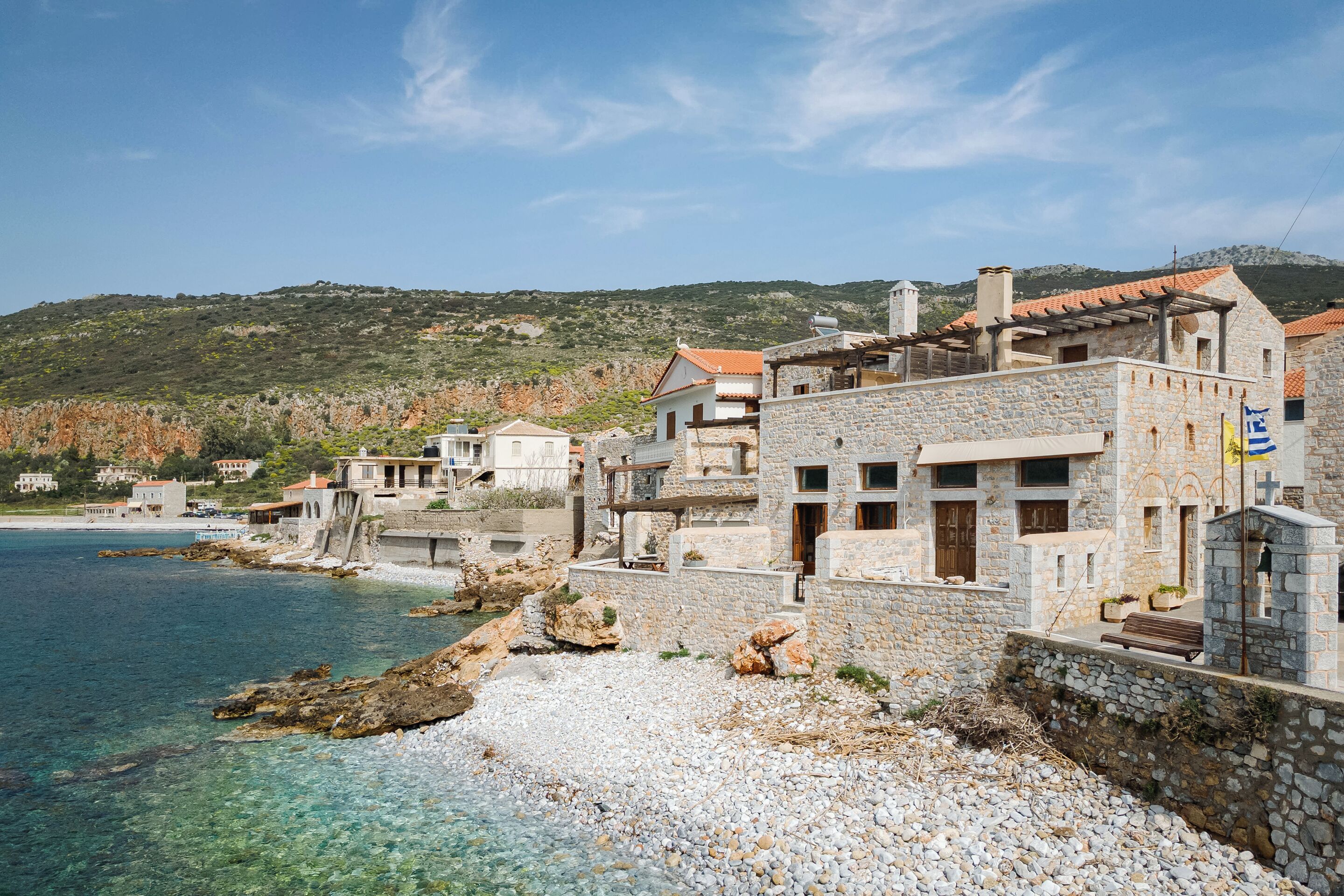 A coastal building with stone walls, a balcony, and a view of the sea.