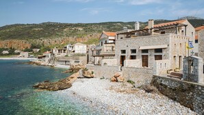 A coastal building with stone walls, a balcony, and a view of the sea. - Aura Seafront Villa (Neo Itilo)