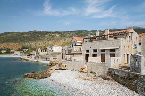 A coastal building with stone walls, a balcony, and a view of the sea. - Aura Seafront Villa (Neo Itilo)