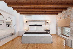 A bedroom with a wooden ceiling, stone wall, and a large bed.