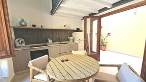 Een keuken met eethoek, met een ronde houten tafel en twee stoelen.