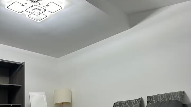 Une chambre à coucher avec un lit, une armoire, une lampe et un luminaire au plafond.