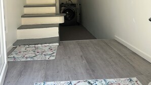 Un escalier menant à un palier où se trouvent un lave-linge et un fauteuil roulant.