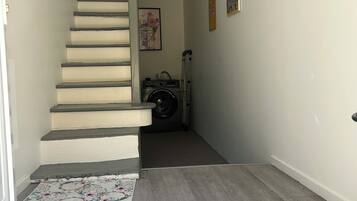 Een trap die uitkomt op een plateau met een wasmachine en een rolstoel.