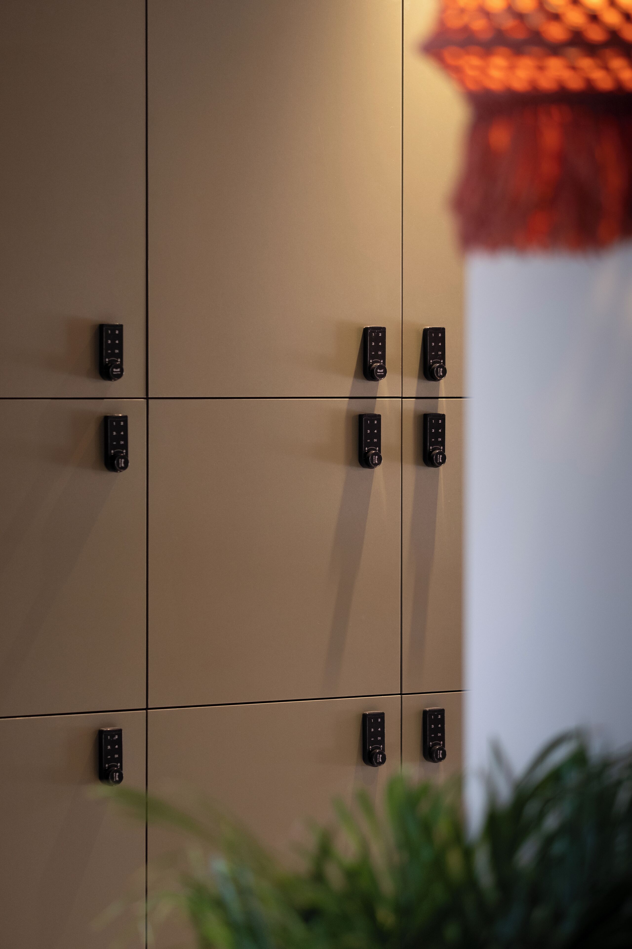 A wall with multiple keypads, likely for room access, and a plant in the foreground.