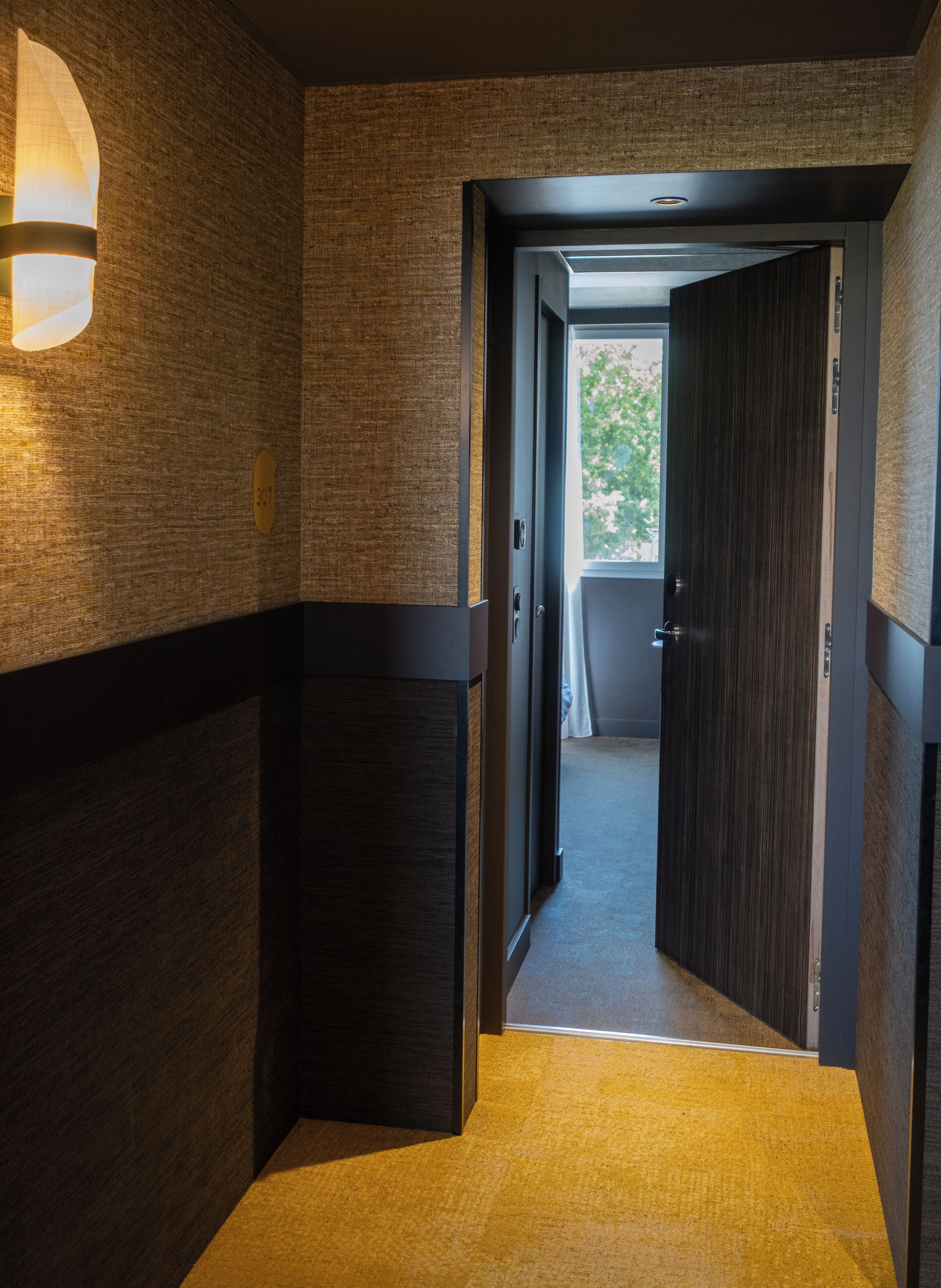 Een gang met een tapijtvloer, houten wanden en een deur naar een balkon.