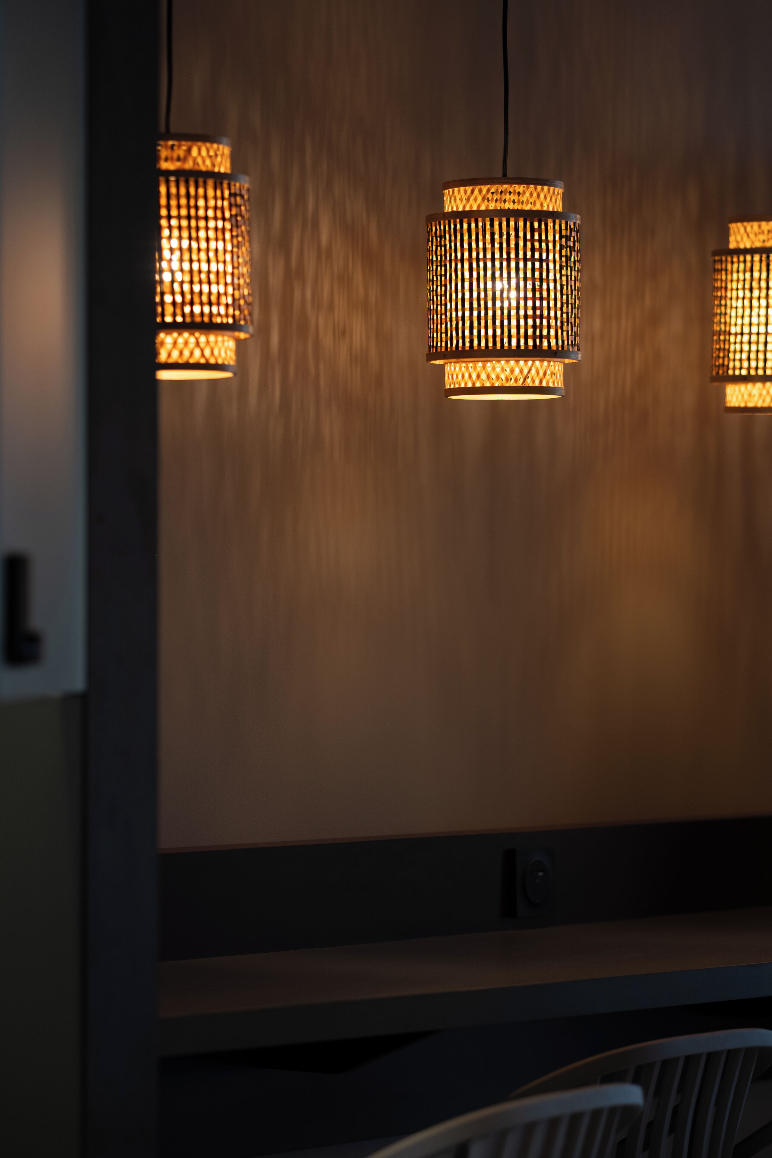 Een muur met drie hanglampen met een geweven patroon.