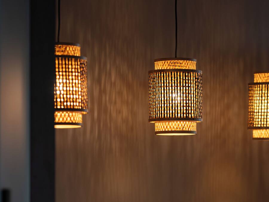 Een muur met drie hanglampen met een geweven patroon.