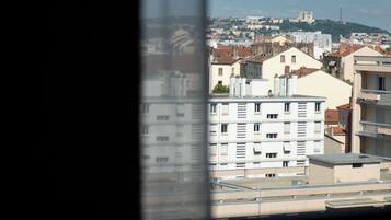 Un paisaje urbano a través de una ventana, con edificios y una colina distante.