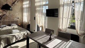A modern bedroom with a bed, a dining table, and a TV. - Studio Sylvinite near Mulhouse (Wittelsheim)