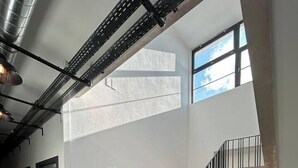 A modern interior with a staircase, metal beams, and large windows. - Studio Sylvinite near Mulhouse (Wittelsheim)