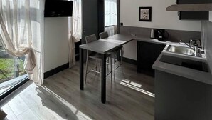 A modern kitchen with a dining area, a large window with sheer curtains, and a flat-screen TV mounted on the wall. - Studio Sylvinite near Mulhouse (Wittelsheim)