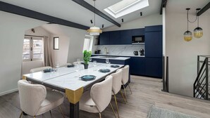 A modern kitchen with dark blue cabinets, a white countertop, and a skylight above the island. - Notre-Dame Family Retreat - Authentic Paris Duplex (Paris)