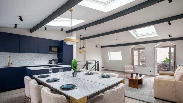 A modern kitchen with dark blue cabinets, a marble countertop, and a skylight. - Notre-Dame Family Retreat - Authentic Paris Duplex (Paris)